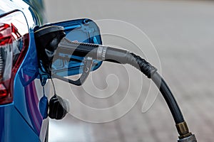 Car fueling at gas station, petrol pump filling fuel nozzle in fuel tank of car at gas station