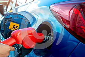 Car fueling at gas station. Refuel fill up with petrol gasoline. Petrol pump filling fuel nozzle in fuel tank of car at gas