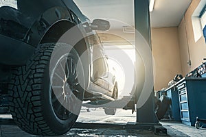 Car in garage of auto repair service shop with special repairing equipment, changing tires
