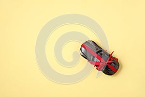 Car gift concept. Modern car with ribbon like a present on yellow background. Top view, flat lay composition