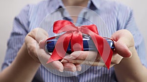 a car a gift for a holiday, a car in a package in female hands, presents in vehicle sales salons, discounts on purchases,