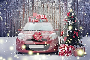 Car with gifts and wreath near Christmas tree in snowy forest