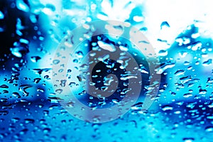 Car glass in raindrops. Water texture on a transparent surface. Toned photo