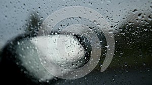 Car glass on a rainy day - defocused background. Moving waterdrops in the wipers of the windshield