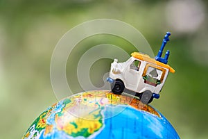 A car on globe on green background. Miniature car toy on globe. Travel concept