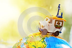 A car on globe on green background. Miniature car toy on globe. Travel concept