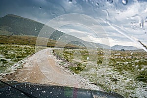 Car going on the muddy road after storm with hailstones in mountain near Lukomir, Bosnia and Herzegovina