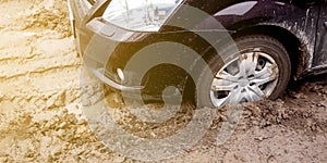 The car got stuck on a dirt road in the mud. Wheel of a car stuck in the mud