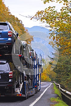 Car hauler semi truck transporting cars on spectacular autumn hi