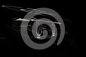 Car headlight on black background. Exterior detail.