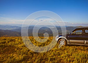 Car at hill along the mountains, against blue sky