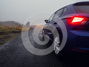 Car illuminating small narrow bridge in a country side, low visibility due to fog. Dangerous road situation because of state of