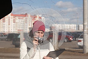 Car insurance agent taking a picture of wrecked car to calculate the damage on a claim form