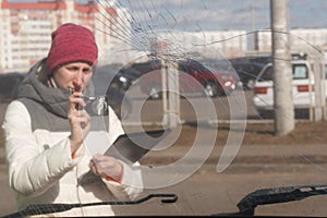 Car insurance agent taking a picture of wrecked car to calculate the damage on a claim form