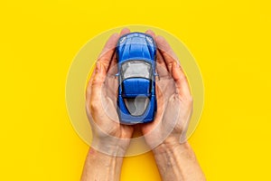 Car insurance concept. Toy car in hands, top view