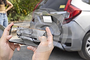 Car insurance and payout concept, damaged vehicles with a smartphone as a proof of insurance claim