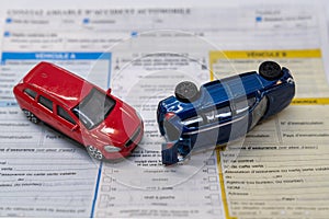 Car insurance report following an accident concept with toy cars on accident statement