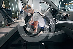 Car interior chemical cleaning by professional detailer in respirator