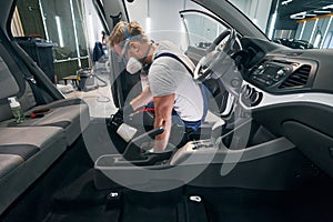 Car interior chemical cleaning by professional detailer in respirator photo
