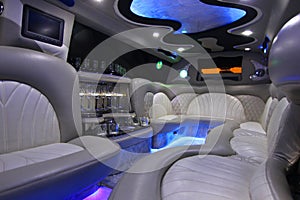 Car interior with comfortable sofas, bar and lights