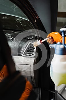 Car interior detailing. Foam and detergent cleaning air system using brush. Worker in auto cleaning service clean car