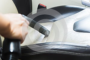 Car interior detailing vacuuming dust from the crevices of car seat