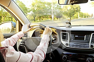 Car interior with female driver sitting behind the wheel, soft sunset light. Luxurious vehicle dashboard and electronics.