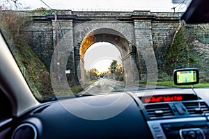 Car interior view of traveling below railroad bridge in UK