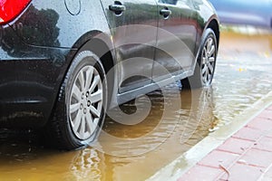 A car in Israel drives through a large puddle of rainwater. The photo illustrates cloudy weather: flood, rain