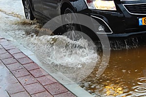 A car in Israel drives through a large puddle of rainwater. The photo illustrates cloudy weather: rain, flood