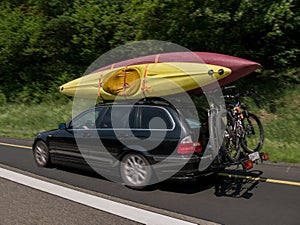 Car with kayaks on the top and bicycles on the back going for holiday