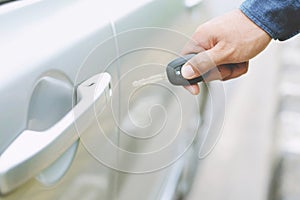 Car key in business man hand. hand presses on the remote control car alarm systems.