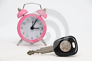 Car key with coin with alarm clock in background.