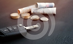 Car key and coins on black background, concept photo for car finance industry