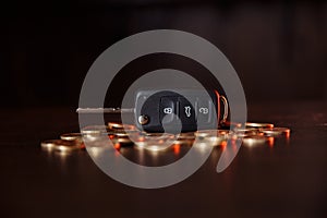 Car key with coins on wooden table. Concept of the saving money for car, trade car for cash