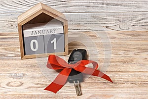 Car key with colorful bow and calendar, on wooden background