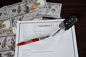 Car key and money on contract of car purchase on wooden table
