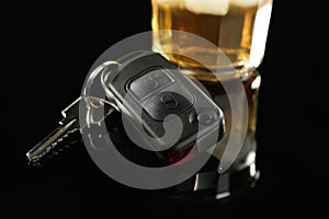 Car key near glass of alcohol on black table, closeup. Dangerous drinking and driving