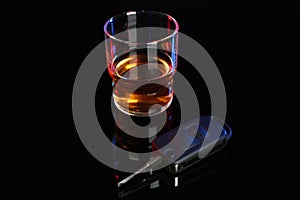 Car key near glass of alcohol on black table. Dangerous drinking and driving