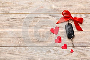 Car key with a red bow and a heart on Colored table. Giving present or gift for valentine day or christmas, Top view