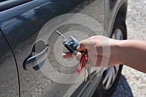 Car key in woman's hand, next to vehicle