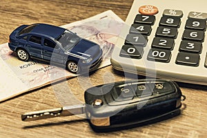 Car keys, banknotes, car model, and calculator as the concept of buying or renting a car