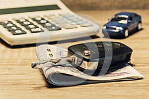 Car keys, banknotes, car model, and calculator as the concept of buying or renting a car