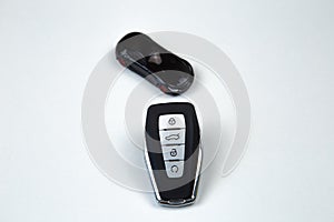 The car keys are black with metal inserts and automatic opening and closing buttons lying on the side on a white