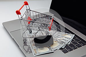 Car keys with dollar banknotes and shopping cart on laptop's keyboard. Online purchase car concept