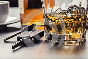 Car keys and glass of alcohol on table.
