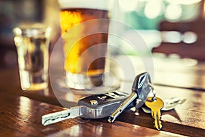 Car keys and glass of beer or distillate alcohol on table in pub or restaurant
