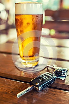 Car keys and glass of beer or distillate alcohol on table in pub or restaurant photo