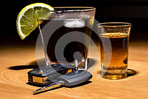 Car keys laid on the bar beside cocktail and whiskey