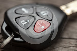 Car keys with remote control alarms on wooden background.